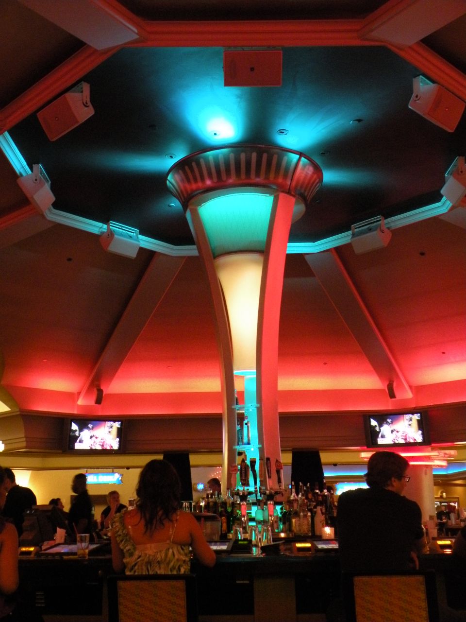 People at a bar with colorful lights and TVs
