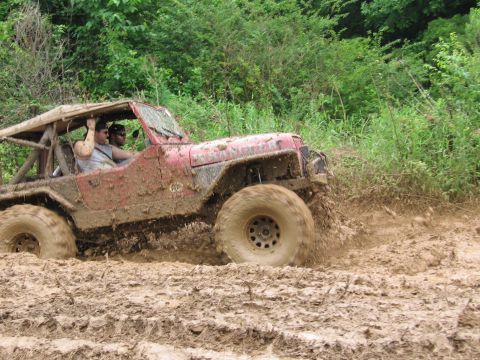 1967 Ford Mustang - This off-road vehicle navigates a challenging muddy terrain, with its tires deep in the mire.