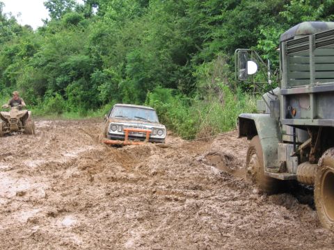 1967 Ford Mustang - Two off-road vehicles and an ATV navigate a muddy trail, with one vehicle being towed.