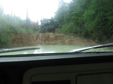 1967 Ford Mustang - A dark truck is stuck in a muddy hill, viewed from the interior of a green vehicle.
