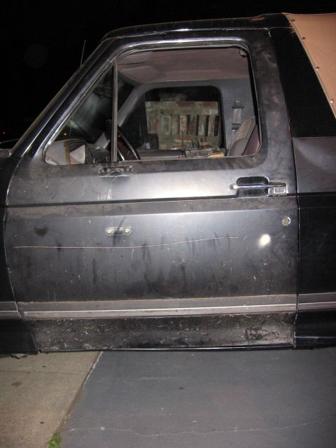 1989 Ford Bronco - The side of a black Ford Bronco is visible, with a focus on the driver's door and the interior cabin.