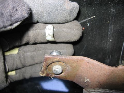 1989 Ford Bronco - Gloved hands manipulate a metal bracket with visible bolts and a plastic clip.