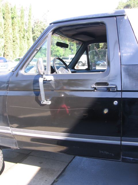 1989 Ford Bronco - Side view of a black 1989 Ford Bronco, focusing on the driver's side door and interior details.