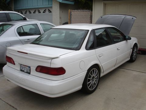 1993 Ford Taurus - A white sedan with its hood open is parked in a driveway next to a silver car.