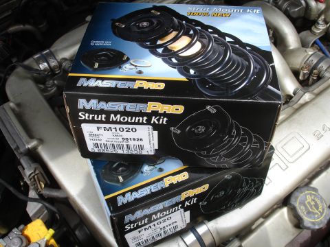 1993 Ford Taurus - Boxes of MasterPro Strut Mount Kits are shown resting on engine parts.