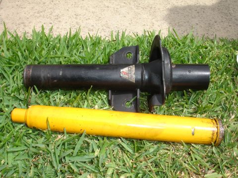 1993 Ford Taurus - A car strut and its associated spring assembly are displayed on a grassy surface.
