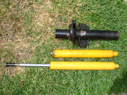 1993 Ford Taurus - Two yellow car struts and one black strut assembly are laid out on the grass.
