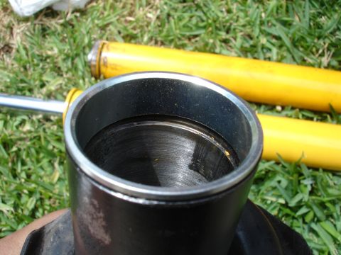 1993 Ford Taurus - Close-up view of a shock absorber cylinder and two yellow shock bodies on grass.