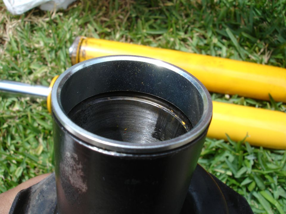 Close-up of a car strut assembly with two yellow shock absorbers in the background on grass