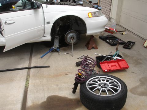 1993 Ford Taurus - Front suspension repair in progress on a 1993 Ford Taurus, with tools and parts laid out.