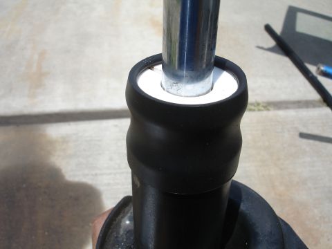 1993 Ford Taurus - Close-up of a vehicle's shock absorber component against a concrete background.
