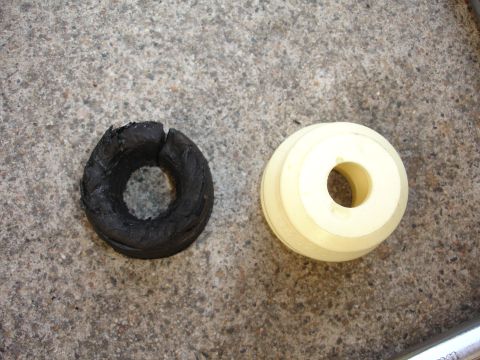 1993 Ford Taurus - Comparison of a damaged rubber strut mount and a new polyurethane replacement, highlighting wear and tear on automotive suspension componen…