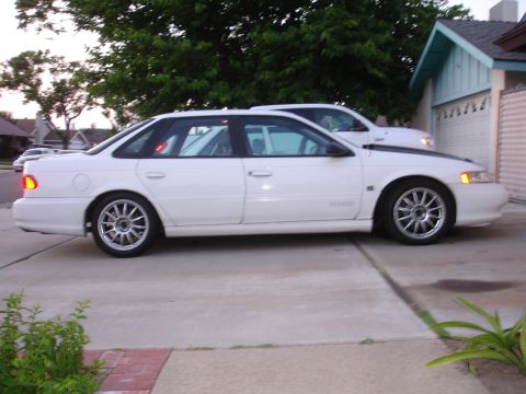 1993 Ford Taurus - Side view of a white 1993 Ford Taurus with custom wheels parked in a driveway.
