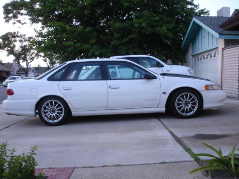 1993 Ford Taurus - A white sedan is parked in a driveway with a house and garage visible in the background.