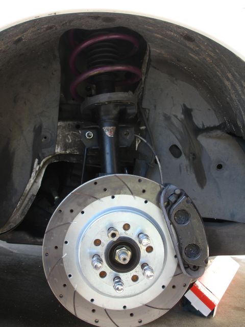 1993 Ford Taurus - Close-up of a vehicle's front strut and brake assembly, a purple coilover spring and a drilled brake rotor.