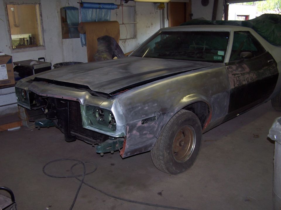 1970s Ford Ranchero sanded to bare metal with front clip stripped, sitting in a garage