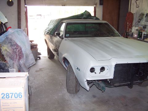 1975 Ford Ranchero - A 1975 Ford Ranchero is undergoing repairs in a garage, with its front end removed and the rear covered by a tarp.