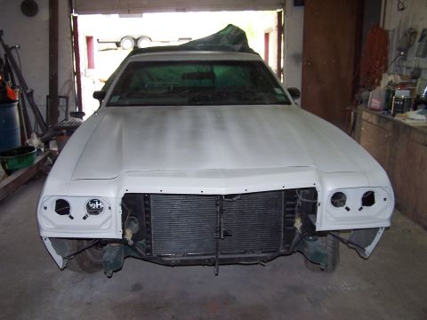 1975 Ford Ranchero - A 1975 Ford Ranchero sits in a garage, its front end disassembled and covered in primer.