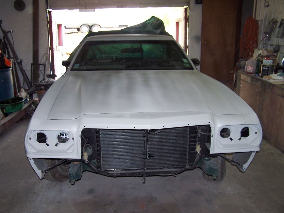 Front view of primered 1970s Ford Ranchero in garage with grille and bumper removed