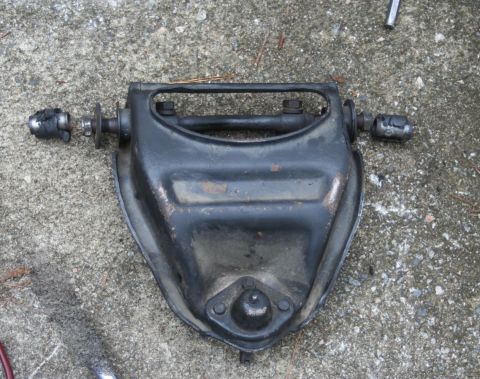 1976 Ford Ranchero - A black automotive suspension control arm assembly rests on a concrete surface.