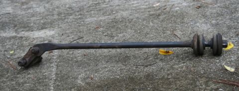 1976 Ford Ranchero - A single suspension linkage part rests on a textured concrete surface with scattered leaves.