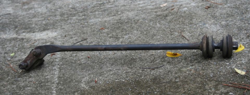 Dark metal suspension linkage with rubber bushings on a concrete surface