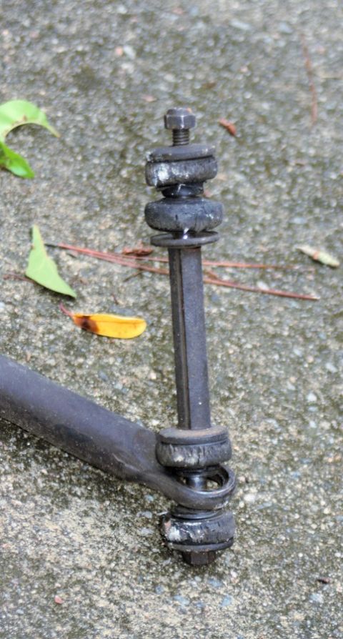 1976 Ford Ranchero - A suspension linkage part is shown in detail, resting on a concrete surface.