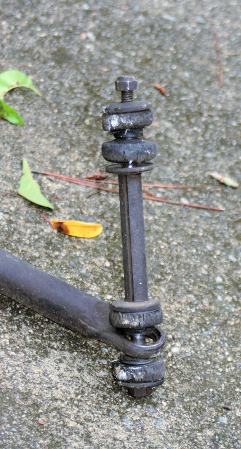 Close-up of a suspension linkage with rubber bushings and a bolt