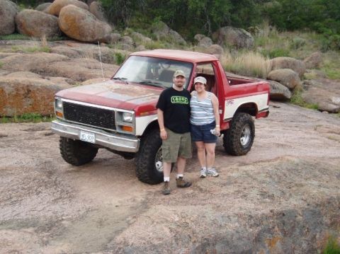 1986 Ford Bronco - A couple poses with their lifted Ford Bronco in a rocky, outdoor setting.