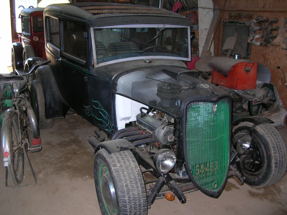 Black hot rod with green flames and a green grille, showing exposed engine and front wheels