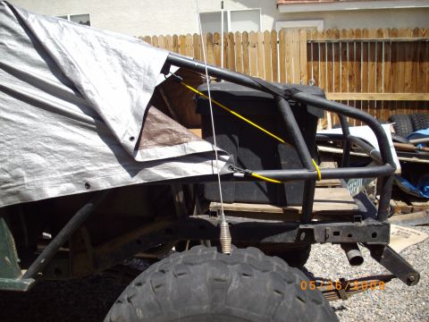 1982 Toyota 4Runner - Custom roll cage and large tire visible on an off-road vehicle, partially covered by a tarp.