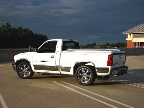 2002 Chevrolet Silverado 1500 - A white 2002 Chevrolet Silverado 1500 pickup truck is parked on a concrete surface under a cloudy sky.