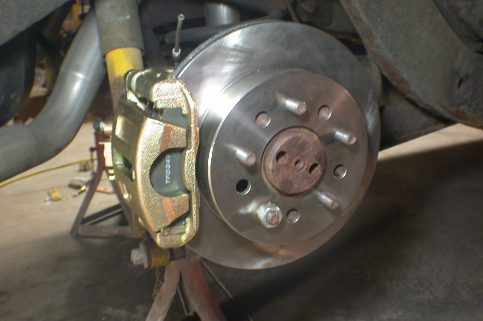 Front disc brake rotor and gold caliper installed on a vehicle hub