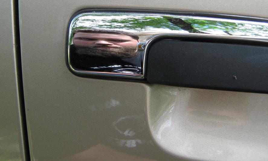reflection of a man's face and beard in chrome door handle