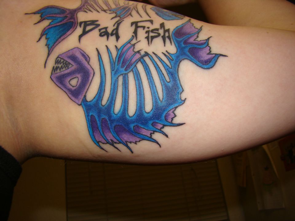 Tattoo of a blue and purple fish skeleton with "Bad Fish" text