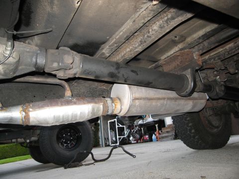 1986 Ford Bronco - The undercarriage of a vehicle is shown, focusing on the driveshaft and exhaust system components.