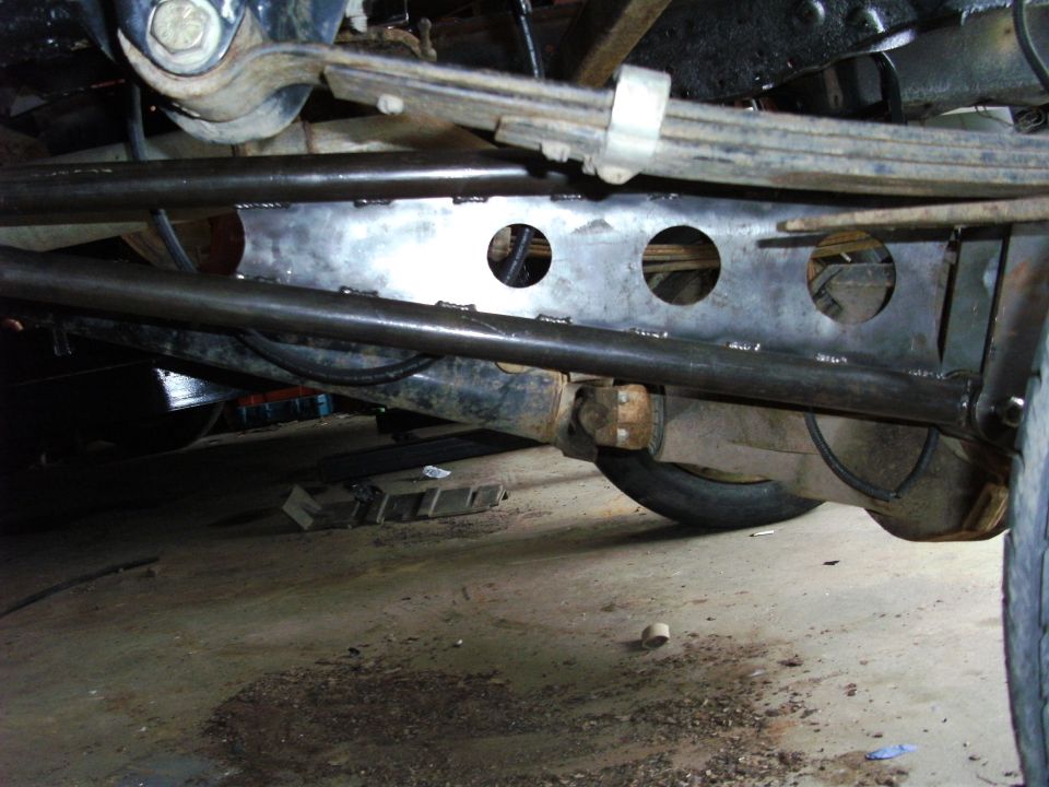Undercarriage view of truck suspension with leaf springs and differential. Visible "SUPERMOTORS" logo