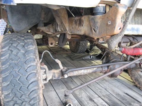 1978 Ford Bronco - Close-up of the undercarriage of a 1978 Ford Bronco, focusing on the front axle and suspension components.