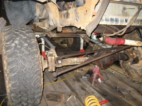 1978 Ford Bronco - The front suspension and wheel of a 1978 Ford Bronco are visible, showing significant rust on the chassis.