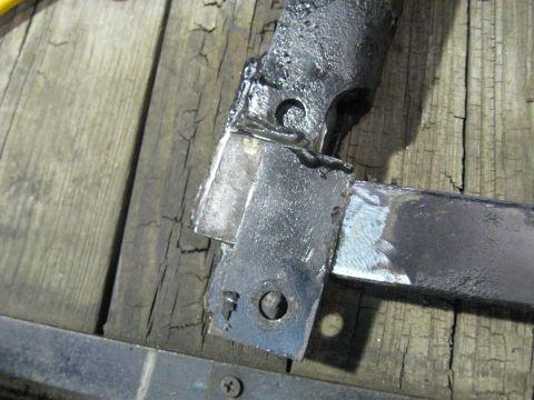1978 Ford Bronco - Close-up of a welded metal bracket attached to wooden planks, likely a component from a vehicle or machinery.