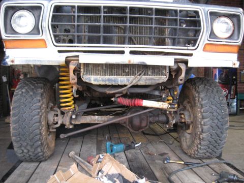 1978 Ford Bronco - The front suspension and radiator of a 1978 Ford Bronco are visible, with tools on the wooden surface below.