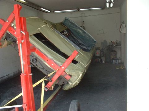 1970 Ford Torino - Car body on a lift, covered in a tarp, in a garage setting with tools and supplies visible.