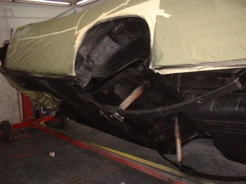 1970 Ford Torino - The undercarriage of a vehicle is shown, with parts of the suspension and exhaust system visible, as it undergoes maintenance.