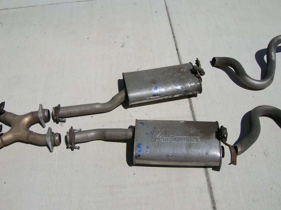 Pair of stainless mufflers labeled XL Performance on pavement