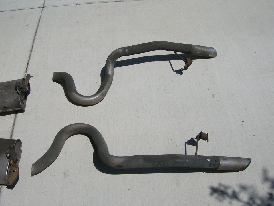 Pair of bent exhaust tailpipes lying on concrete