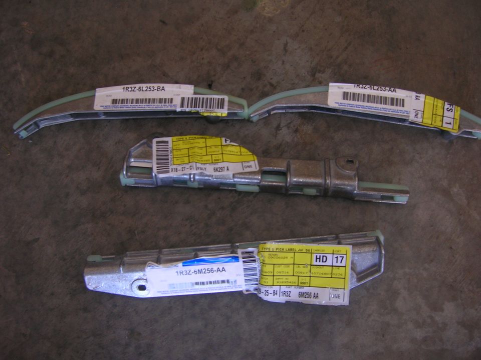 Three timing chain guide rails with Ford part labels on the floor