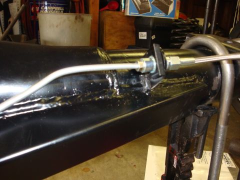 1989 Ford Bronco - Close-up of a vehicle's axle assembly, showing brake line attachment and support jack.