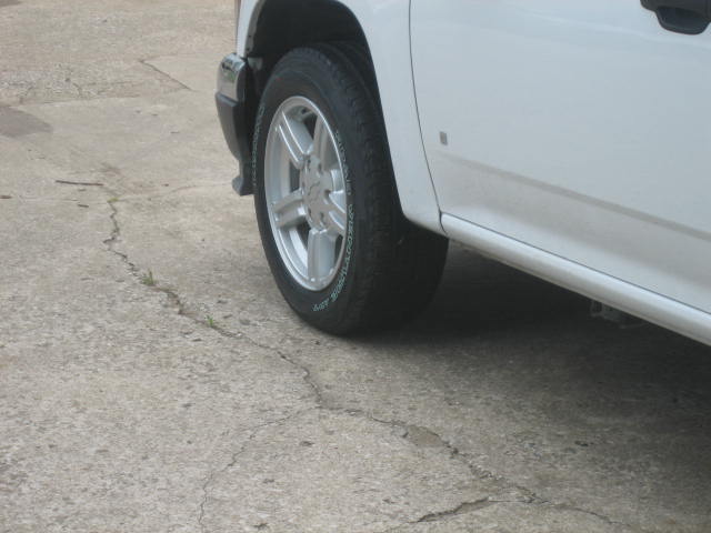 Close-up of a white pickup truck's front wheel and side panel
