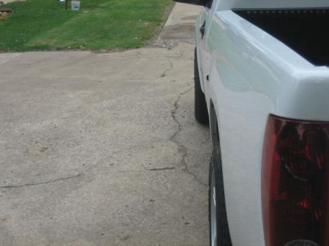 1996 Ford Thunderbird - A white pickup truck is viewed from the side, with a focus on its rear section and a cracked concrete surface.