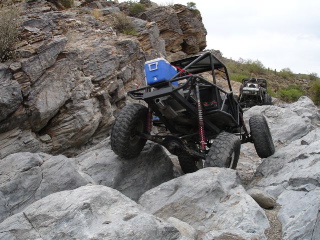 1966 Ford Bronco - Off-road buggy tackles a rocky trail with a cooler secured to its roll cage, while another vehicle follows.